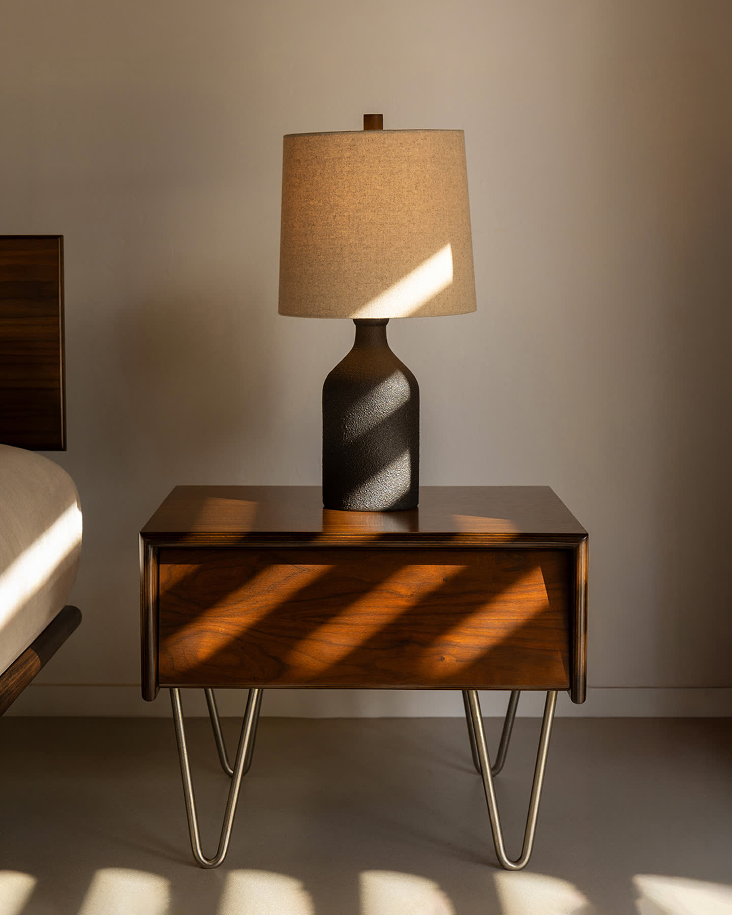 Bottle Table Lamp glowing on a walnut cabinet in warm afternoon light.