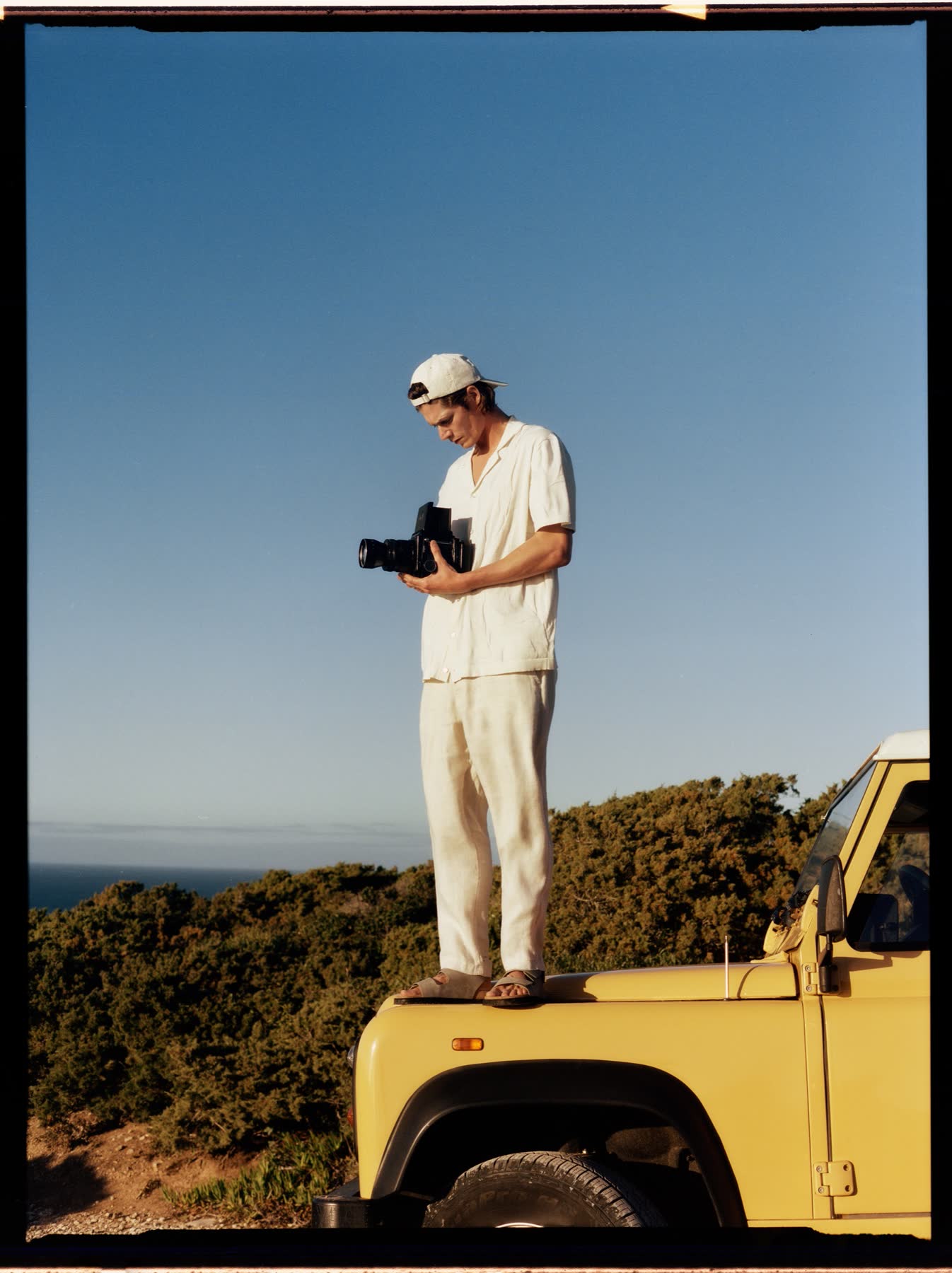 Conrad Leadley standing on a yellow vehicle above Portugal’s Atlantic coast at Cabo da Roca.