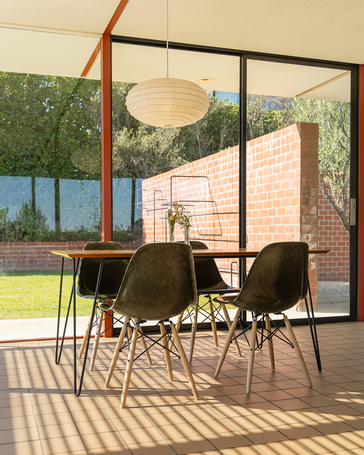 Dining area with molded chairs and a pendant lamp at Case Study House #16.