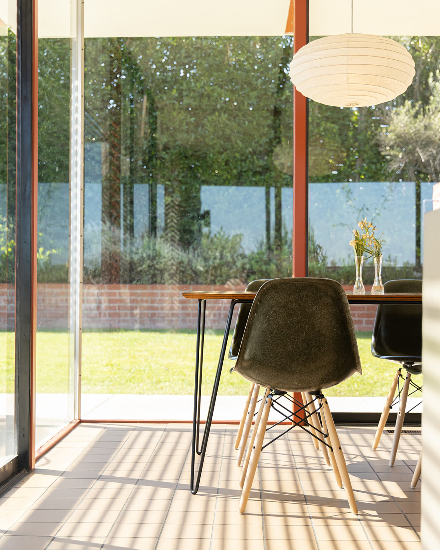 A dining chair and table framed by the glass walls of Case Study House #16.