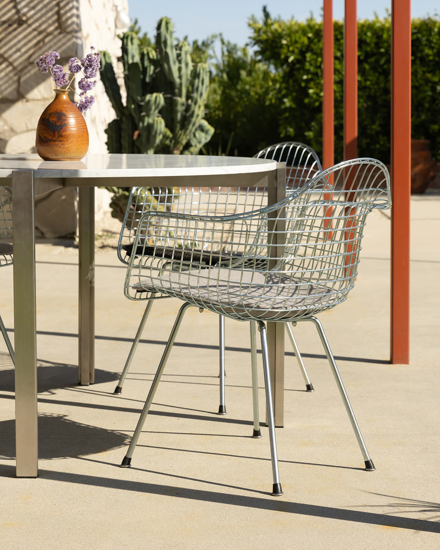A wire chair and marble table in the sun.