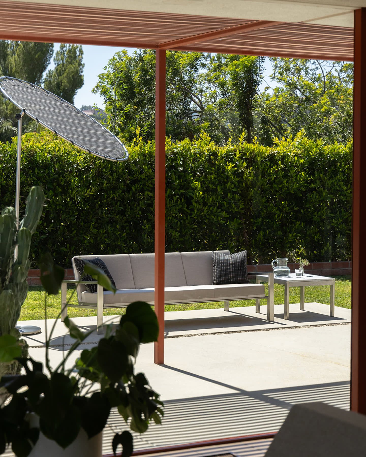 A patio lounge with a wire chair beneath the pergola.