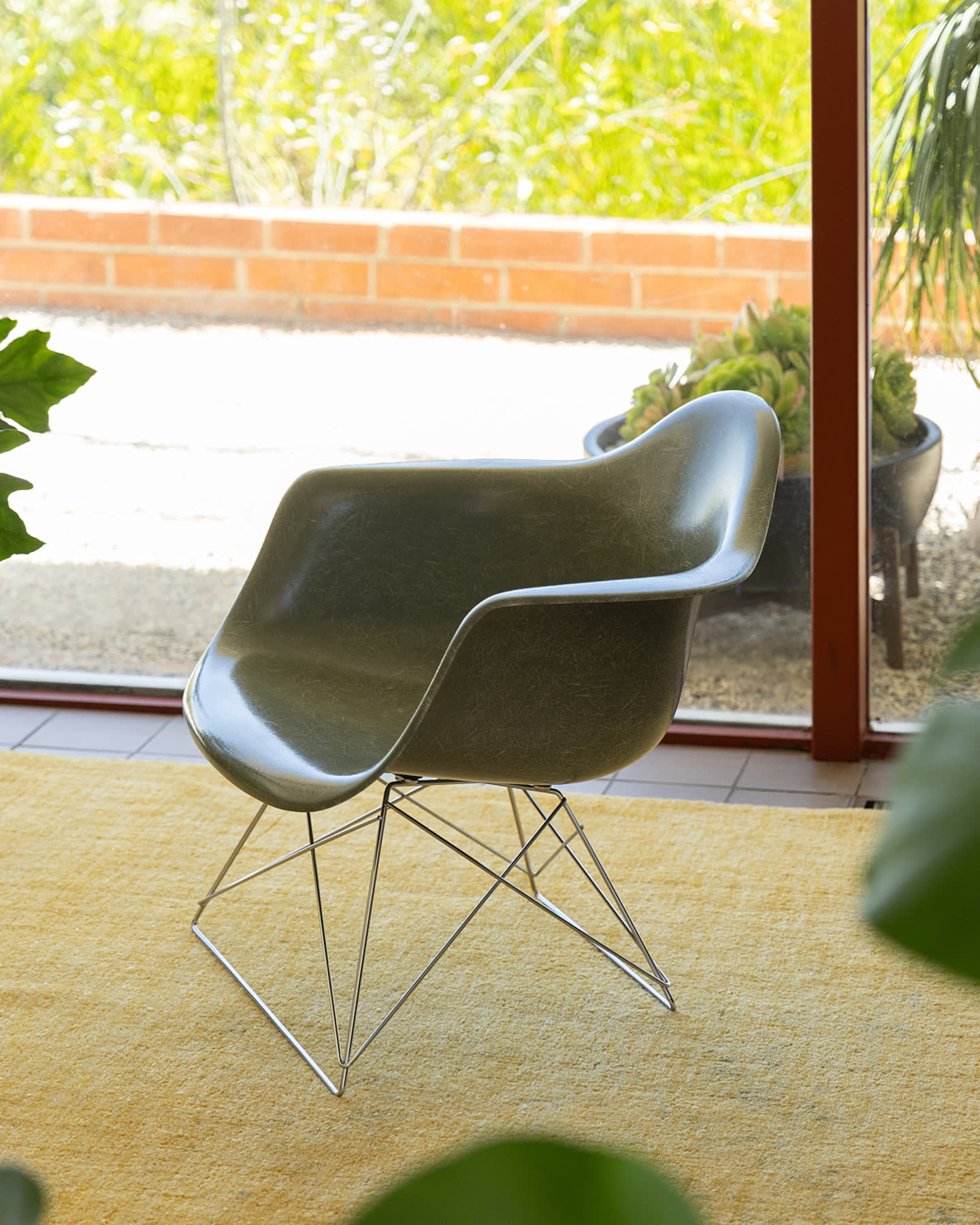A green molded chair on a yellow rug.