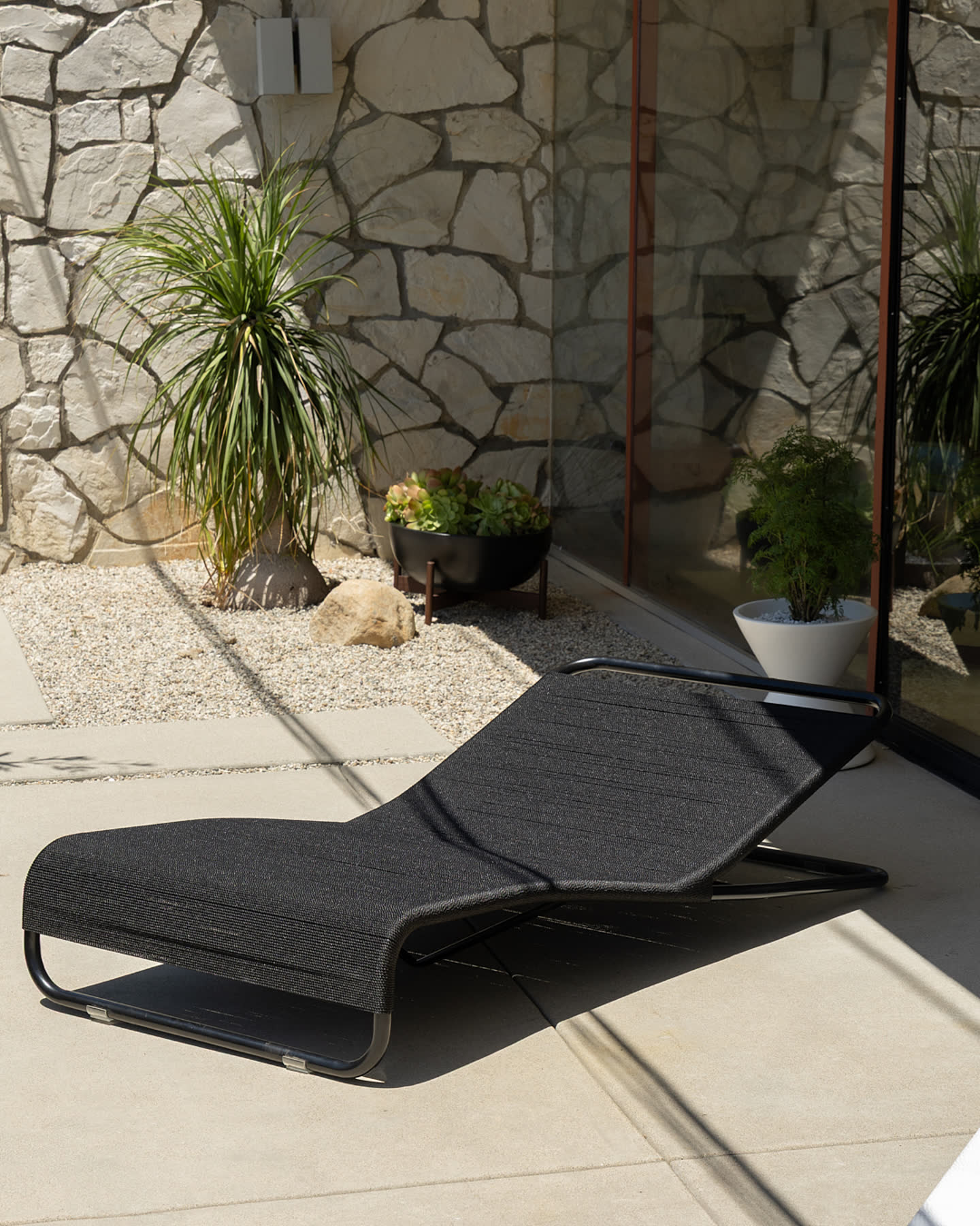 A black daybed set against the stone courtyard wall.
