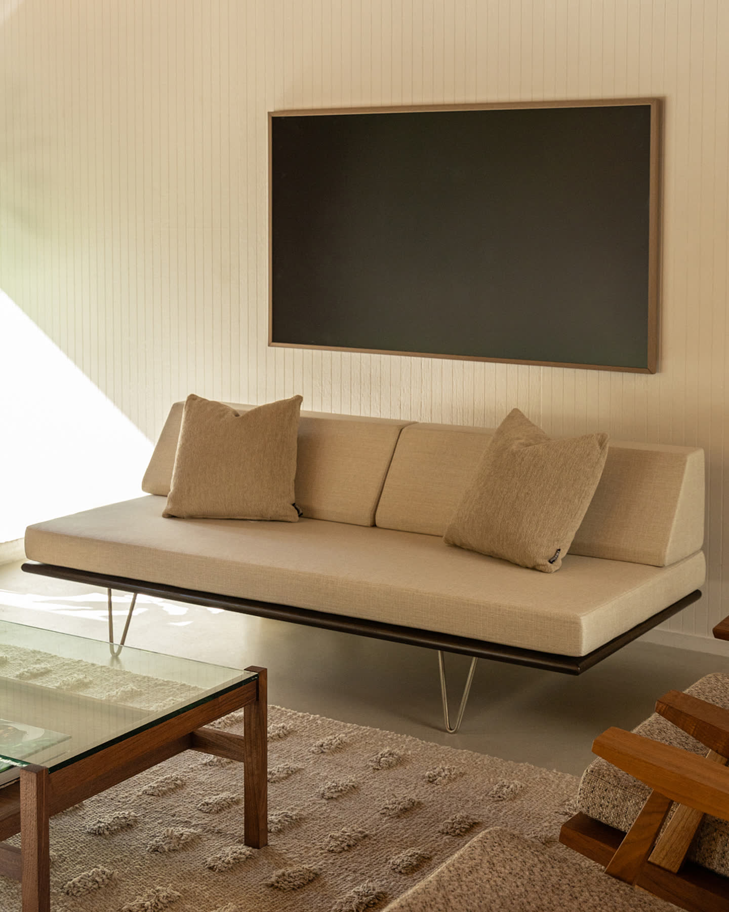 A Modernica sofa beneath a framed screen in the Eichler Post & Beam living room.