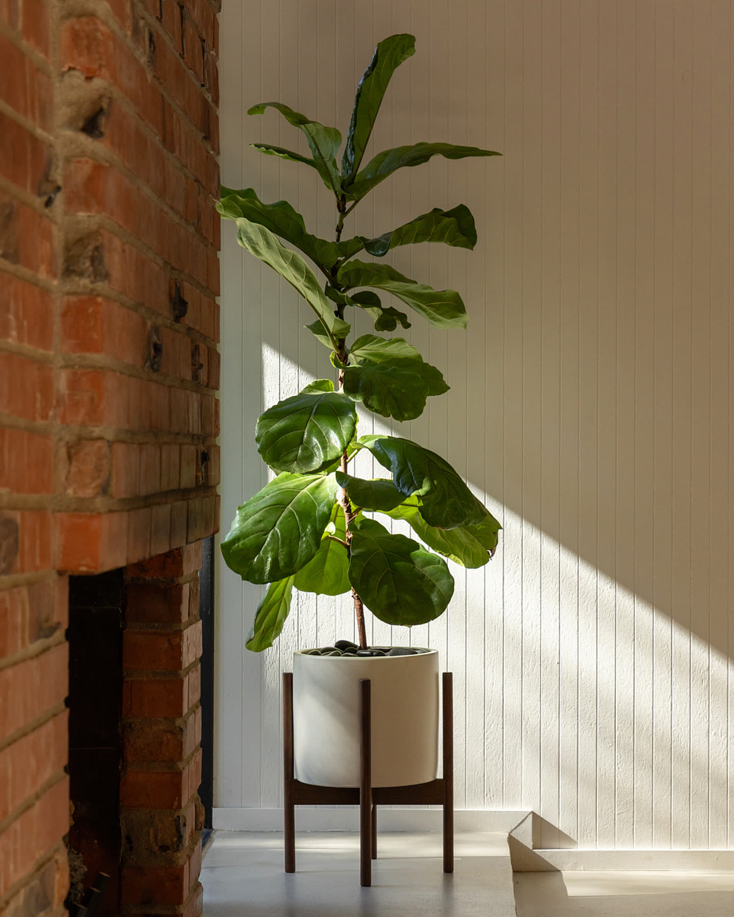 A Modernica planter lit beside the brick fireplace in the Eichler Post & Beam house.