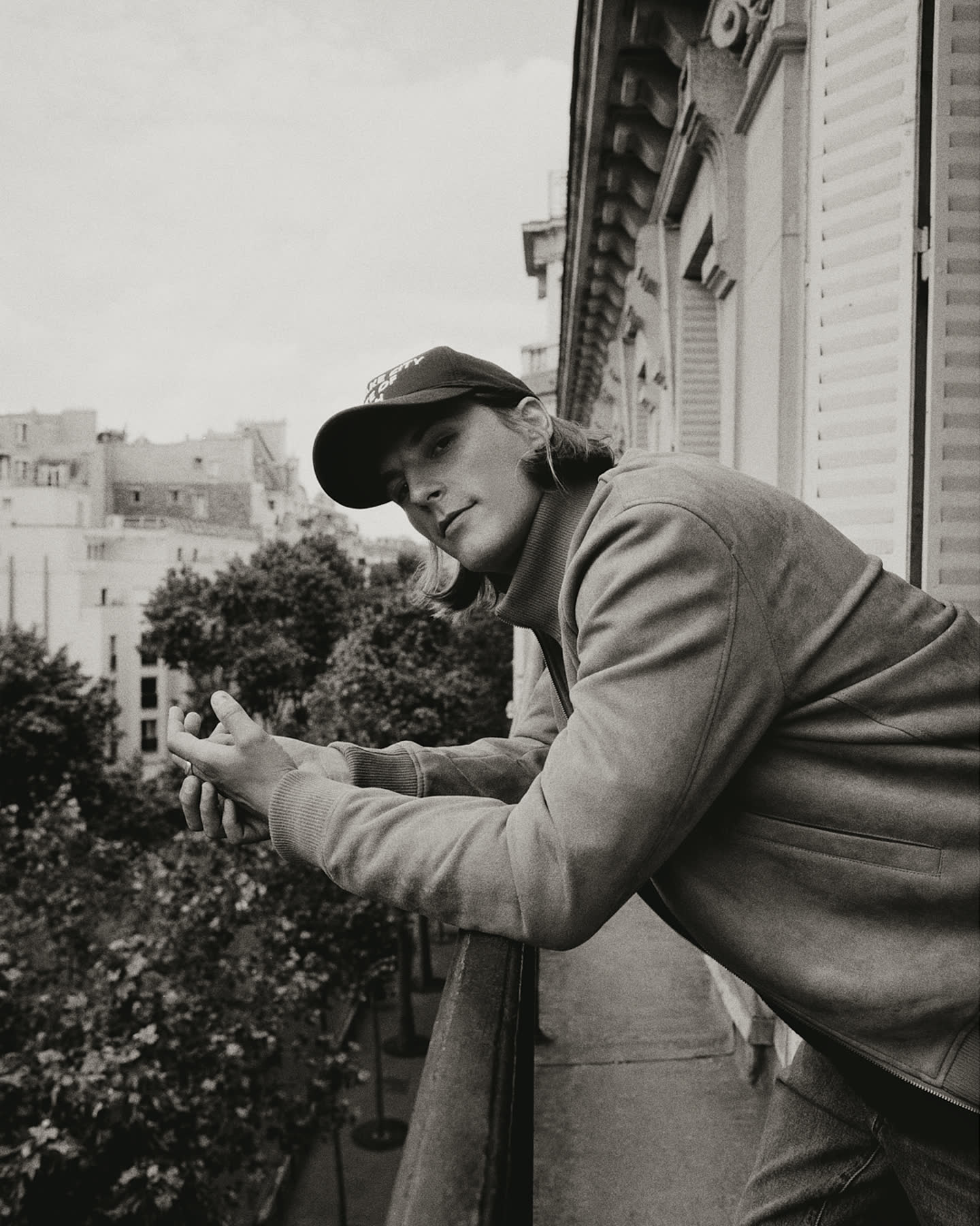 Model leaning from a Parisian balcony for the Haussmann story.