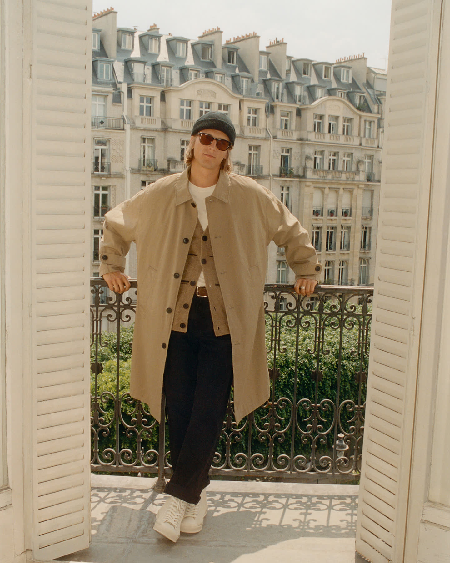 Model standing between open shutters overlooking Paris for the Haussmann story.