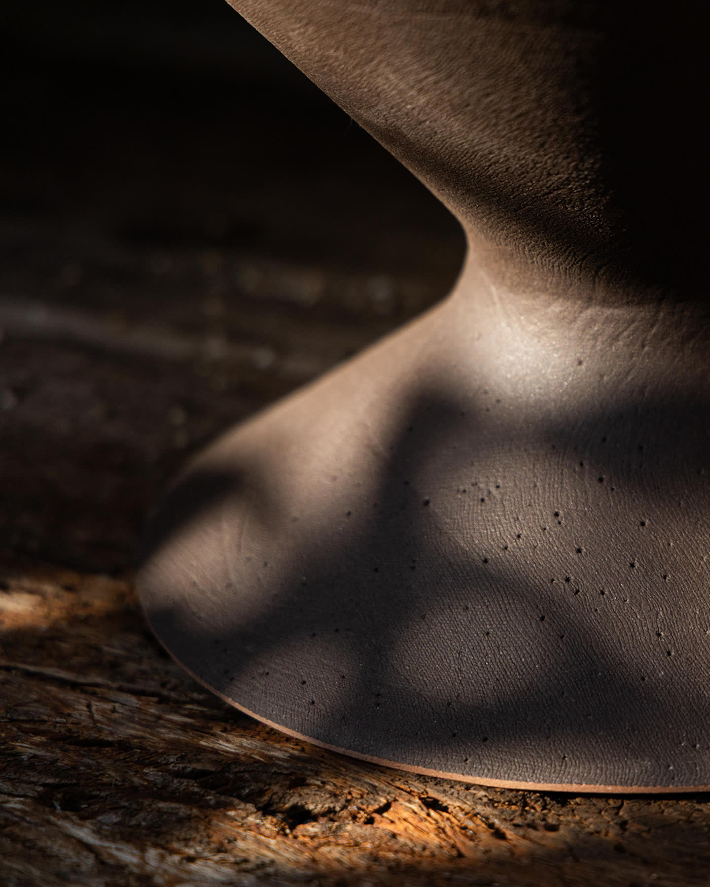 Close detail of the Oblique planter&rsquo;s dark bronze ceramic base.