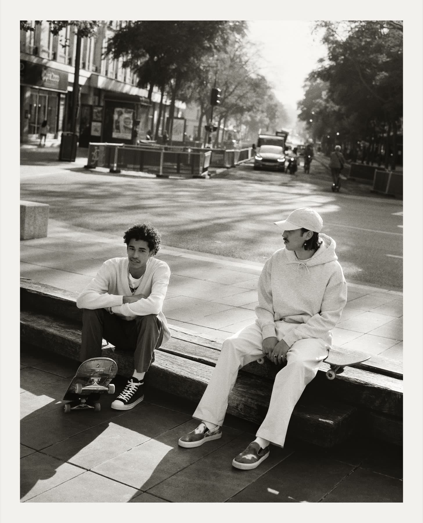 Two skaters sitting beside a Paris street.