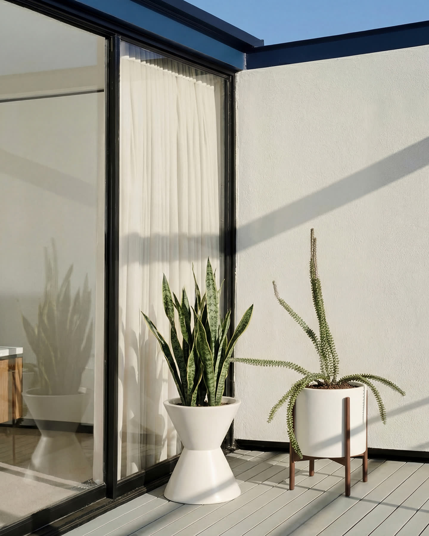White stoneware planters arranged on the sunlit terrace of the Smith House.