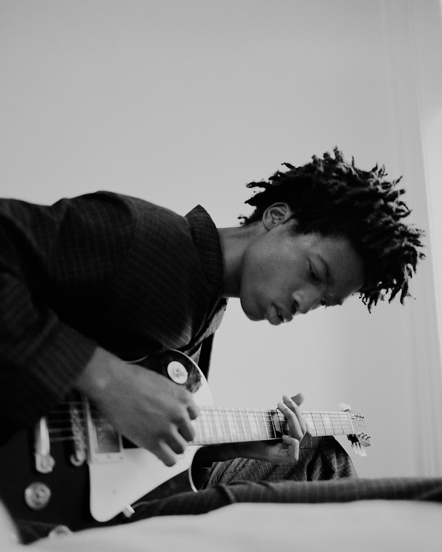 A close black-and-white portrait of Tamel Lee playing guitar.