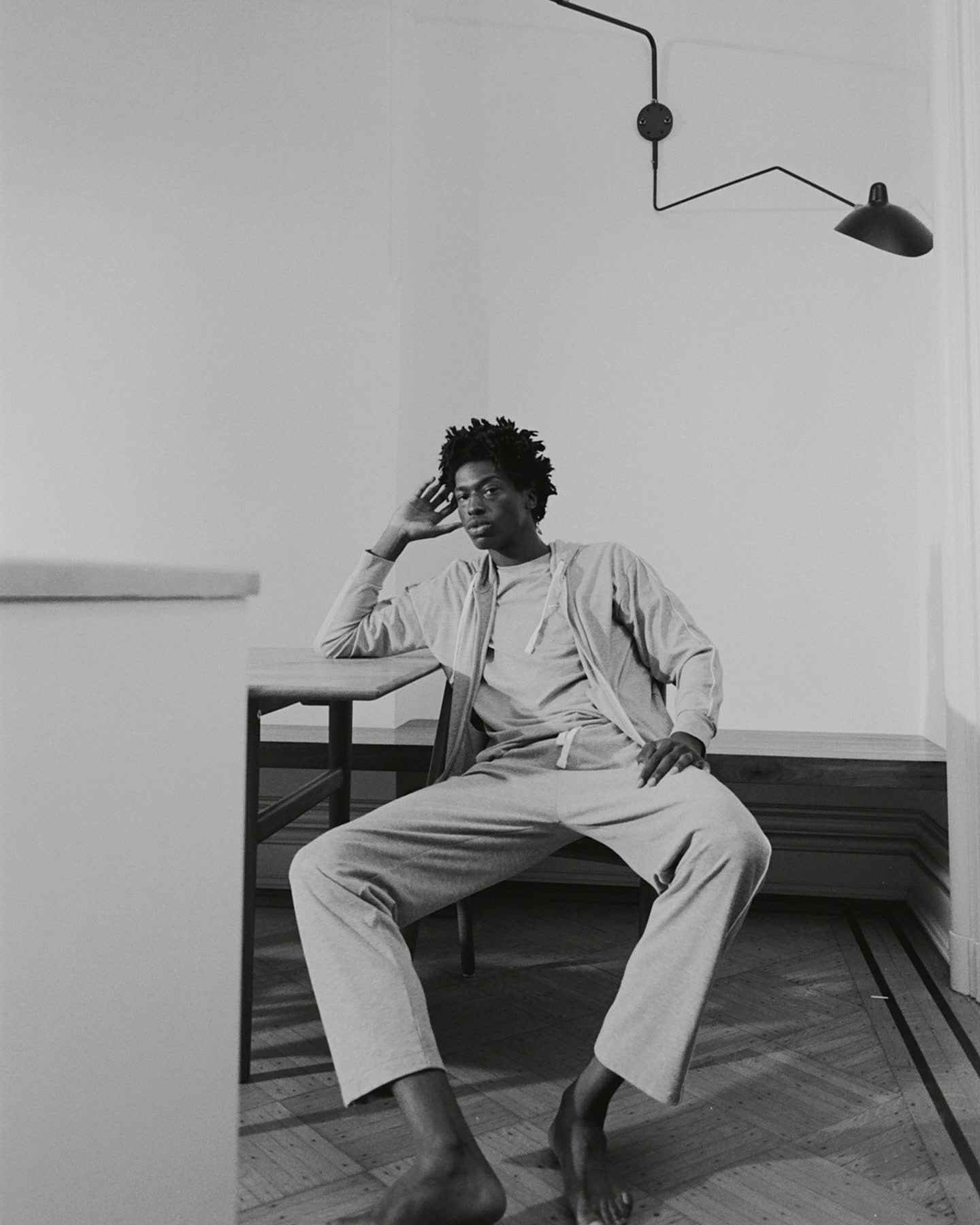 A black-and-white portrait of Tamel Lee seated in the home.