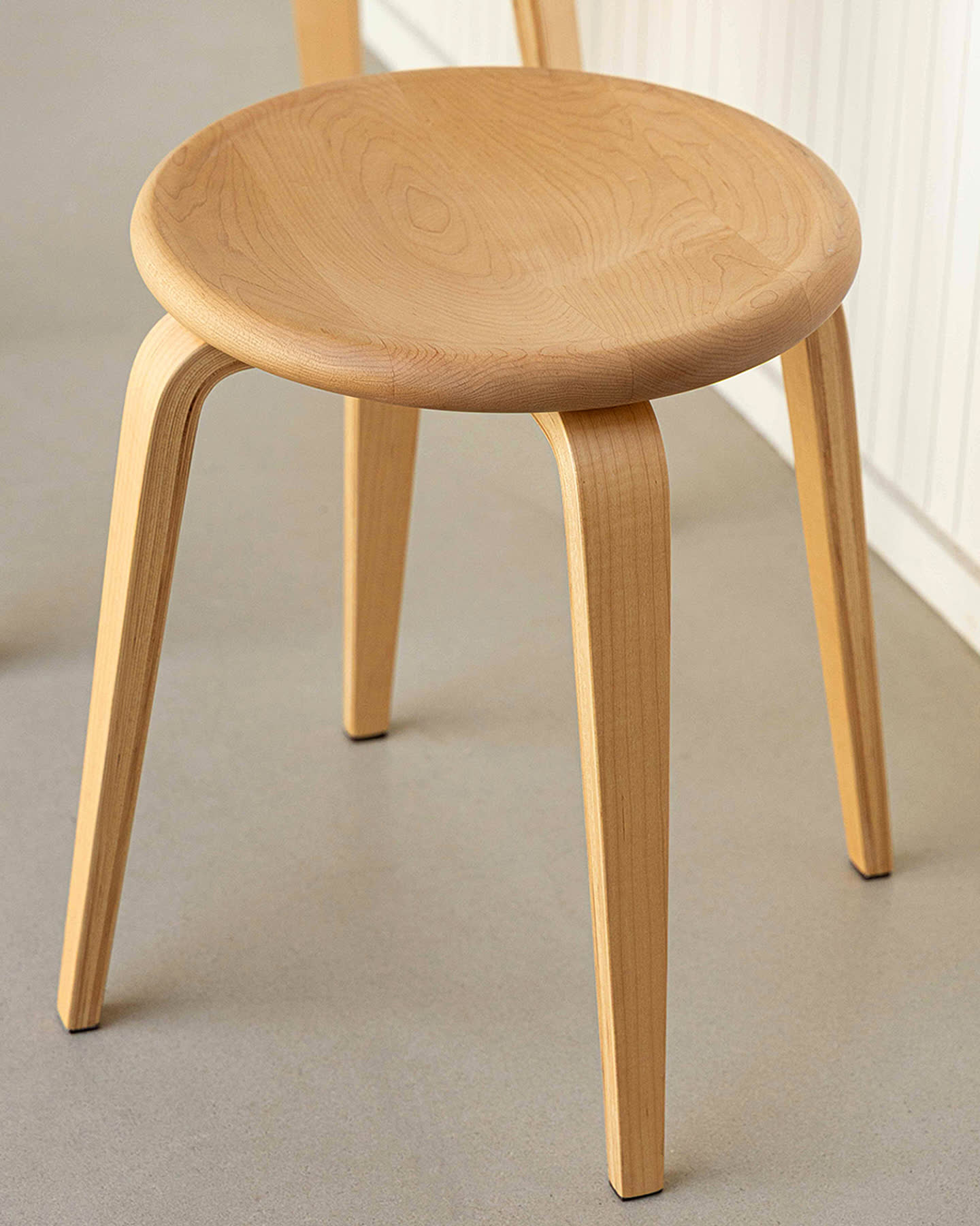Close view of a maple Bistro Collection stool beside the table for Sunroom.