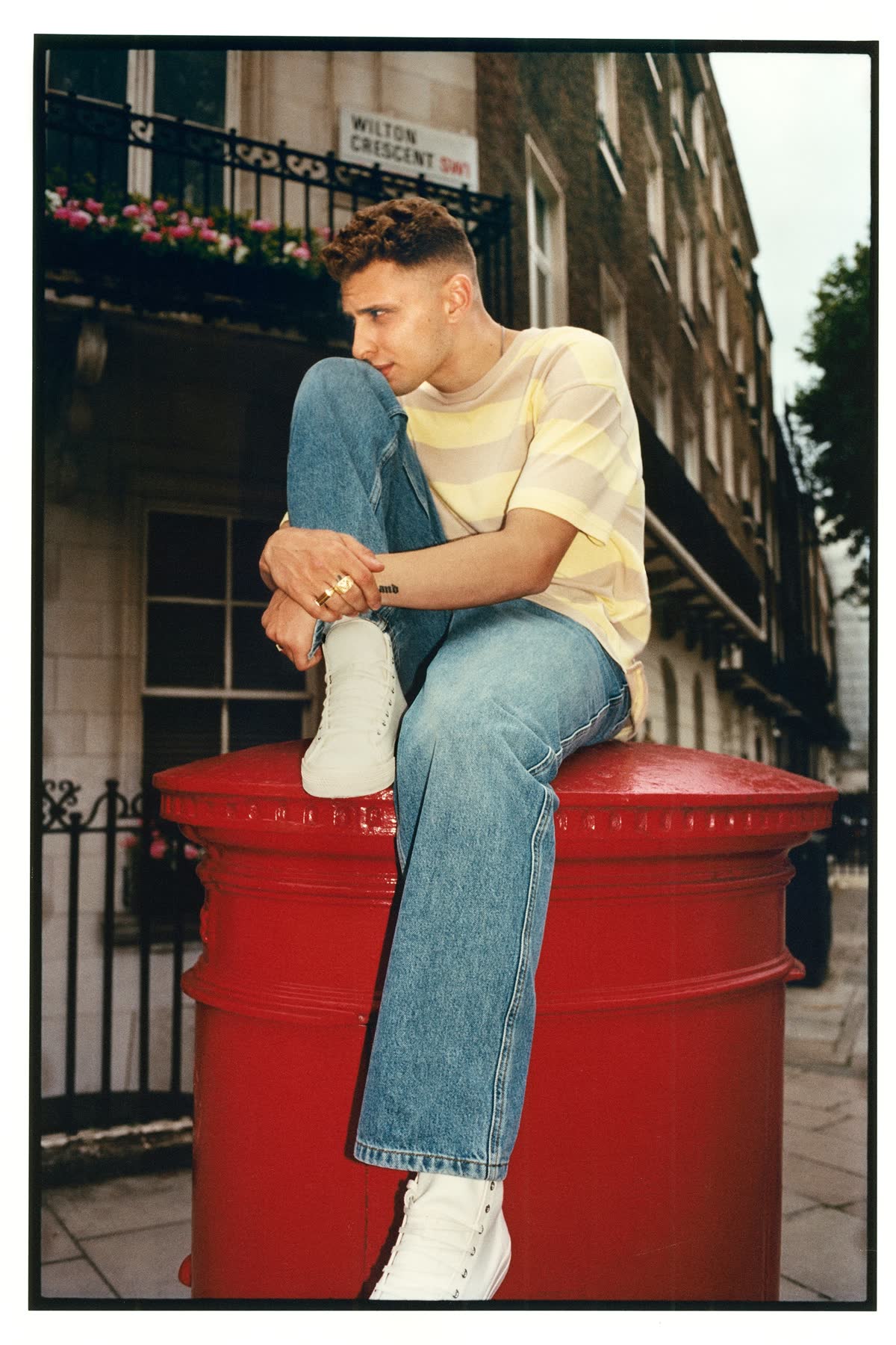 Blondey McCoy seated on a red post in Chelsea for Zara.